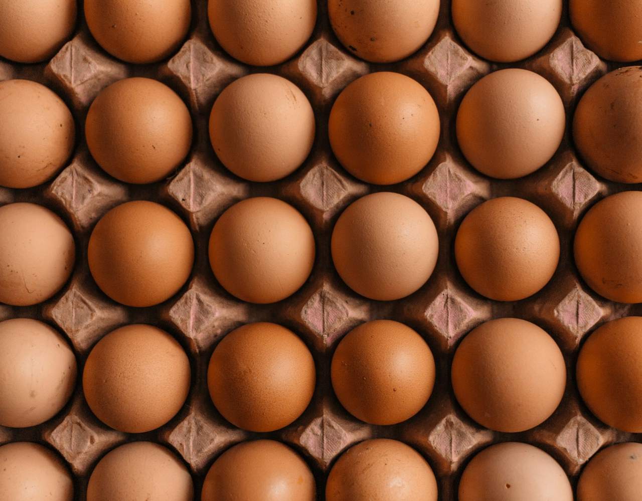 Rows of brown hens' eggs in a moulded cardboard tray seen from above